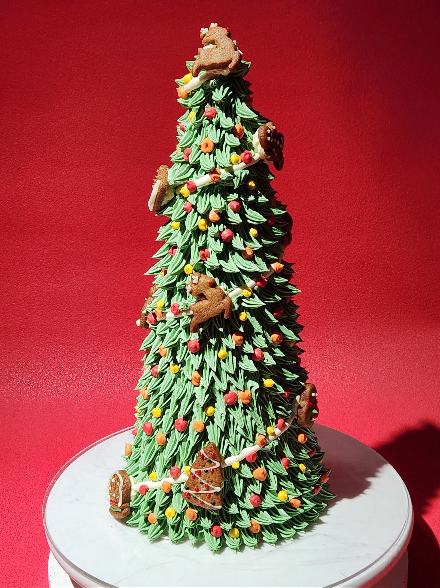 Decorative Christmas tree cake with gingerbread cookies on a red background